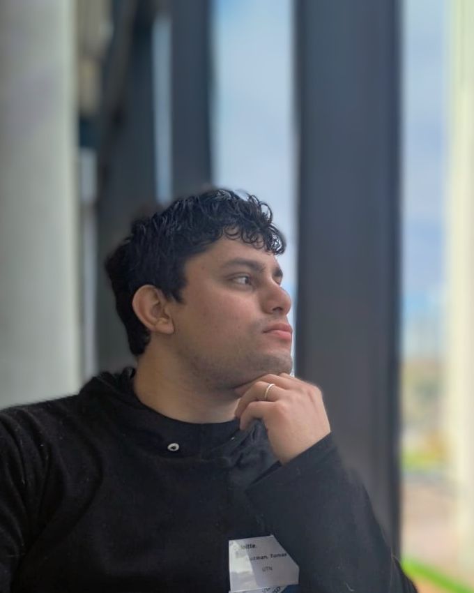 Retrato de Tomas Guzman junto a una ventana, mirando hacia afuera con la mano en el mentón